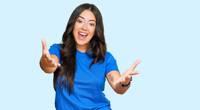 Beautiful brunette young woman wearing casual clothes smiling cheerful offering hands giving assistance and acceptance.