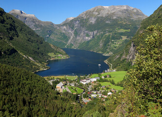 View From Flydalsjuvet Lookout To Geiranger Village And Geirangerfjord On A Sunny Summer Day With A Clear Blue Sky