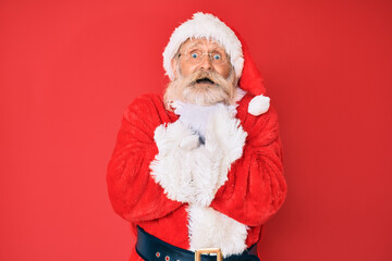 Old senior man with grey hair and long beard wearing traditional santa claus costume shouting and suffocate because painful strangle. health problem. asphyxiate and suicide concept.