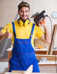 The young repairman carpenter working cutting wood on circular s