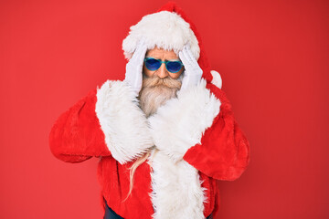 Old senior man wearing santa claus costume and sunglasses suffering from headache desperate and stressed because pain and migraine. hands on head.