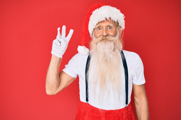 Fototapeta na wymiar Old senior man with grey hair and long beard wearing white t-shirt and santa claus costume showing and pointing up with fingers number three while smiling confident and happy.