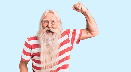 Old senior man with grey hair and long beard wearing striped tshirt angry and mad raising fist...