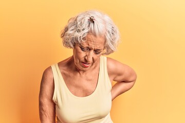 Senior grey-haired woman wearing casual clothes suffering of backache, touching back with hand, muscular pain