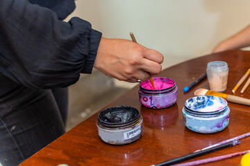 Hand taking paint from the bottle with a brush