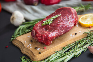 Fototapeta na wymiar Raw beef steak on a cutting board with spices. Creative atmospheric decoration
