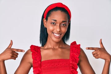 Young african american woman wearing casual clothes looking confident with smile on face, pointing...