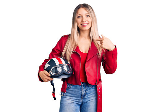 Young beautiful blonde woman holding motorcycle helmet pointing finger to one self smiling happy and proud