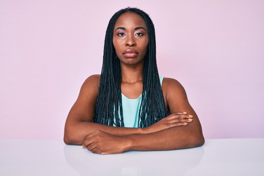 African american woman with braids wearing casual clothes sitting on the table depressed and worry for distress, crying angry and afraid. sad expression.