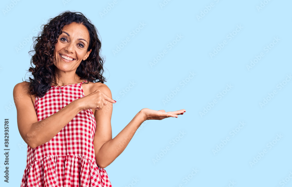 Wall mural middle age beautiful woman wearing casual sleeveless t shirt amazed and smiling to the camera while 