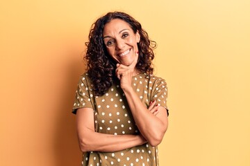 Middle age beautiful woman wearing casual t shirt smiling looking confident at the camera with crossed arms and hand on chin. thinking positive.