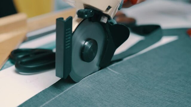 Woman cuts dark fabric with a roller cutting knife