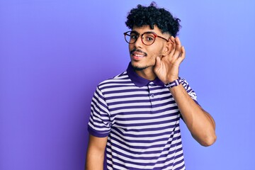Fototapeta na wymiar Young arab handsome man wearing casual clothes and glasses smiling with hand over ear listening and hearing to rumor or gossip. deafness concept.