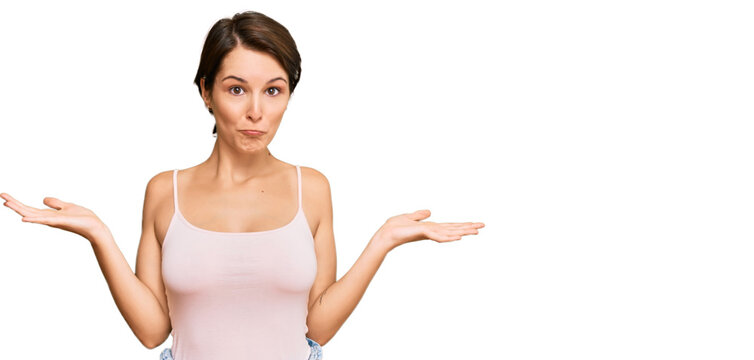 Young brunette woman with short hair wearing casual summer clothes clueless and confused expression with arms and hands raised. doubt concept.