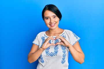 Beautiful young woman with short hair wearing casual clothes smiling in love doing heart symbol shape with hands. romantic concept.
