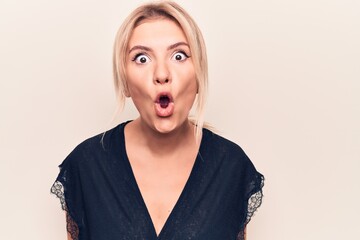 Obraz na płótnie Canvas Young beautiful blonde woman wearing casual t-shirt standing over isolated white background afraid and shocked with surprise expression, fear and excited face.