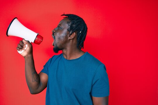 Young handsome african american man screaming using megaphone over isolated red background