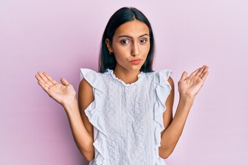 Young brunette woman wearing elegant summer shirt clueless and confused with open arms, no idea and...