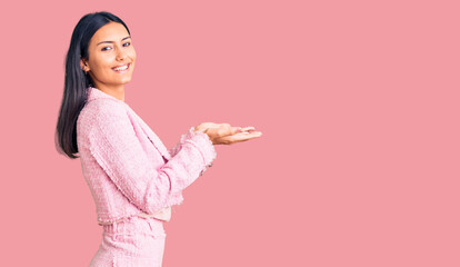 Young beautiful latin girl wearing business clothes pointing aside with hands open palms showing copy space, presenting advertisement smiling excited happy