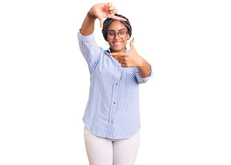 Fototapeta premium Young african american woman with braids wearing casual clothes and glasses smiling making frame with hands and fingers with happy face. creativity and photography concept.