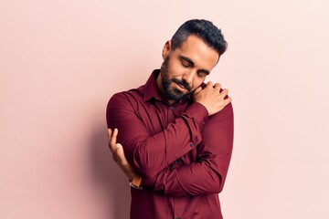 Young hispanic man wearing casual clothes hugging oneself happy and positive, smiling confident. self love and self care