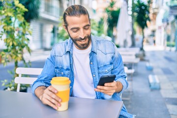 Young middle eastern man using smartphone and drinking coffee at coffee shop.