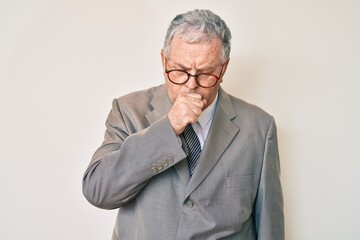 Senior grey-haired man wearing business suit feeling unwell and coughing as symptom for cold or bronchitis. health care concept.