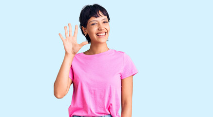 Young brunette woman with short hair wearing casual clothes showing and pointing up with fingers number five while smiling confident and happy.