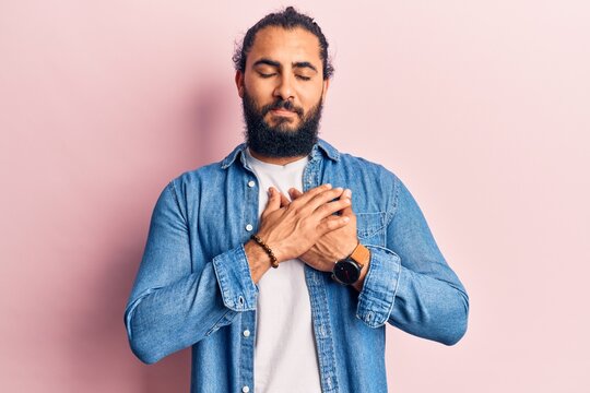 Young arab man wearing casual clothes smiling with hands on chest, eyes closed with grateful gesture on face. health concept.