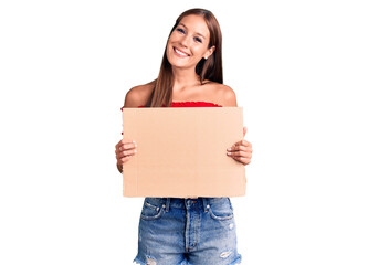 Young beautiful hispanic woman holding banner cardboard looking positive and happy standing and smiling with a confident smile showing teeth