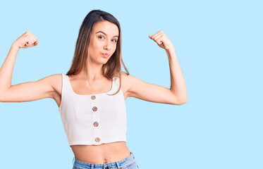 Young beautiful girl wearing casual sleeveless t shirt showing arms muscles smiling proud. fitness concept.