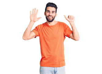 Fototapeta premium Young handsome man with beard wearing casual t-shirt showing and pointing up with fingers number six while smiling confident and happy.