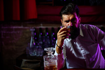 Young man holding glass of whiskey. Guy with beard holds brandy. Bearded drink cognac. Sommelier tastes drink. Man holding a glass of whisky. Sipping whiskey. Degustation, tasting