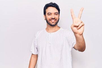 Young hispanic man wearing casual clothes showing and pointing up with fingers number two while smiling confident and happy.