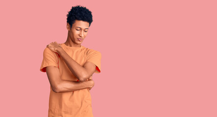Young african american man wearing casual clothes hugging oneself happy and positive, smiling confident. self love and self care