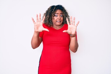 Young african american plus size woman wearing casual clothes afraid and terrified with fear expression stop gesture with hands, shouting in shock. panic concept.