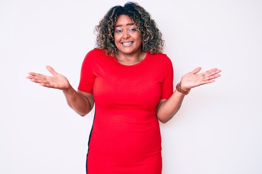 Young african american plus size woman wearing casual clothes clueless and confused expression with arms and hands raised. doubt concept.