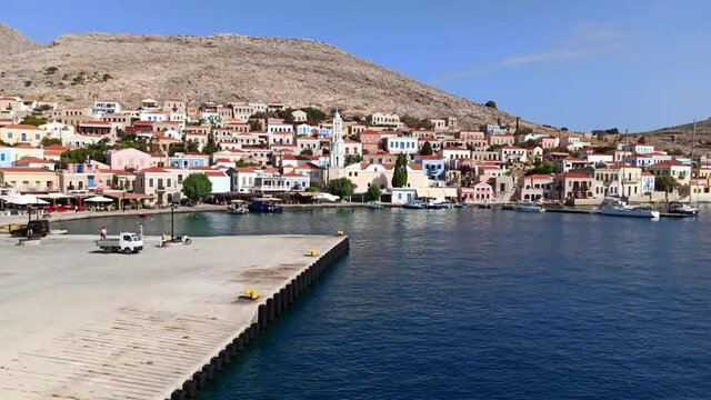 Pan shot of Emporio port of halki / chalki island and houses located on a hills of Greece in the Dodecanese archipelago in the Aegean Sea, some 6 km (4 mi) west of Rhodes