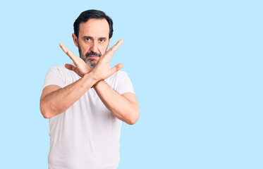 Fototapeta premium Middle age handsome man wearing casual t-shirt rejection expression crossing arms doing negative sign, angry face