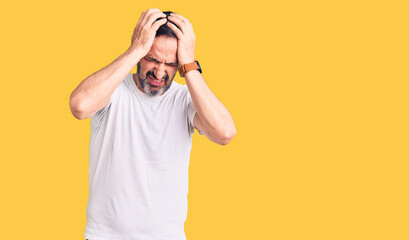 Middle age handsome man wearing casual t-shirt suffering from headache desperate and stressed because pain and migraine. hands on head.