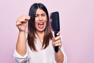 Young beautiful woman agry and worried for capillary problem. Holding hairbrush with tangled hair...