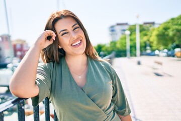 Young hispanic woman smiling happy leaning on balustrade at street of city