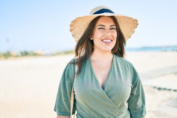 Young hispanic woman on vacation smiling happy walking at the beach