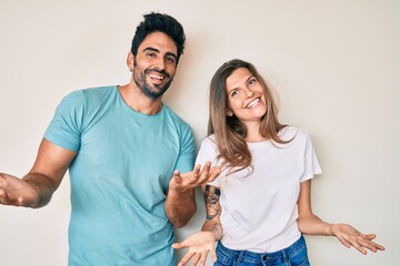Beautiful young couple of boyfriend and girlfriend together smiling cheerful with open arms as friendly welcome, positive and confident greetings