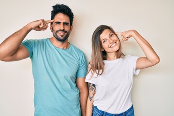 Beautiful young couple of boyfriend and girlfriend together smiling pointing to head with one finger, great idea or thought, good memory