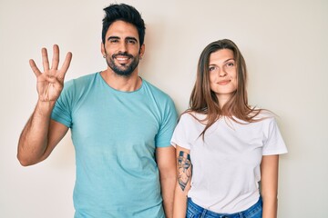 Obraz premium Beautiful young couple of boyfriend and girlfriend together showing and pointing up with fingers number four while smiling confident and happy.