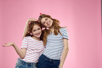 Obraz na płótnie Canvas Cheerful mom and daughter lifestyle joy striped shirts family pink background