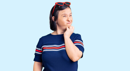 Brunette woman with down syndrome wearing casual clothes looking stressed and nervous with hands on mouth biting nails. anxiety problem.