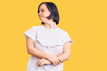 Obraz premium Brunette woman with down syndrome wearing casual white tshirt looking to the side with arms crossed convinced and confident