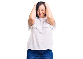 Brunette woman with down syndrome wearing casual white tshirt suffering from headache desperate and stressed because pain and migraine. hands on head.